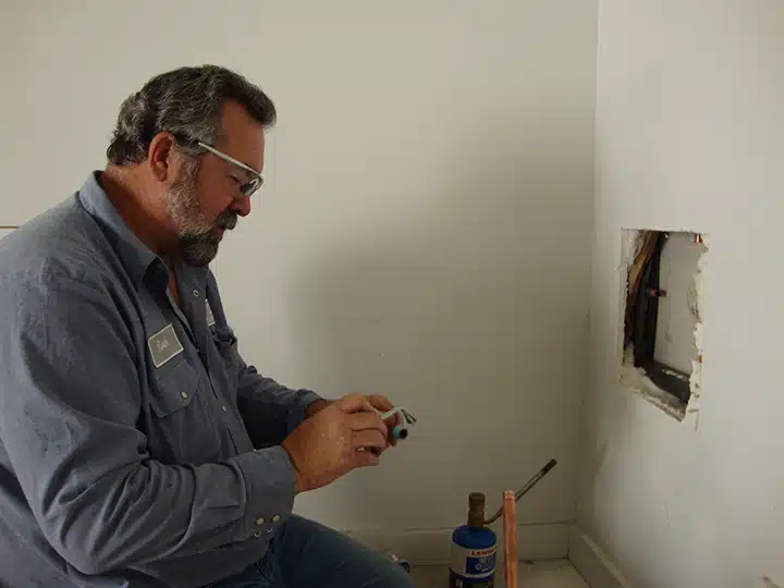 Plumber working on gas line in residential home in Sugar Land, TX.