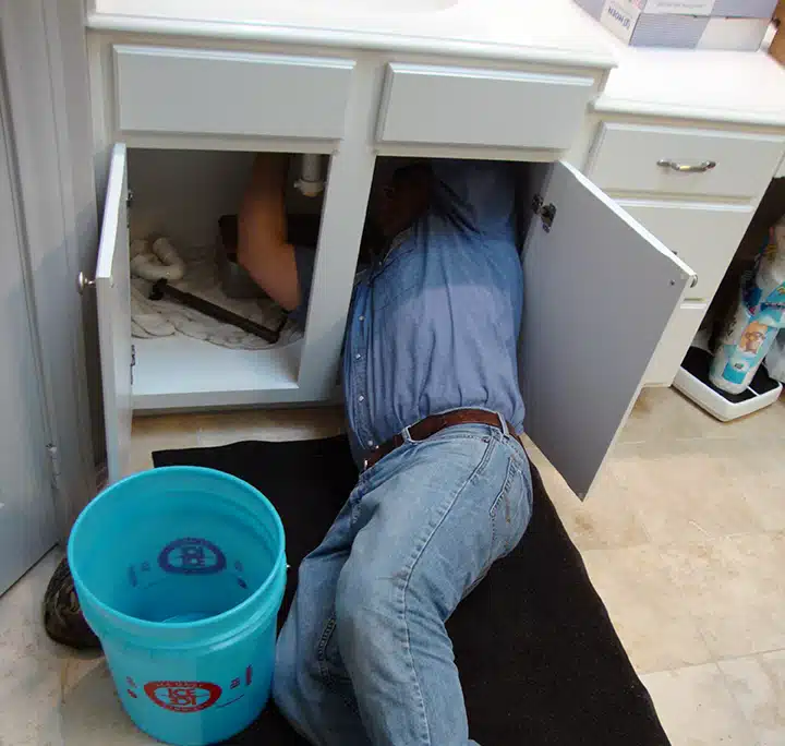 Doug Turner Plumbing CO fixing plumbing under sink in residential home in Sugar Land, TX.